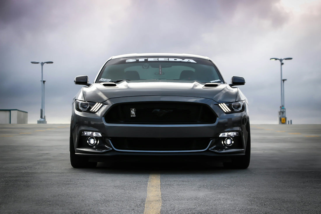 A dark grey Ford Mustang parked on an empty asphalt parking lot